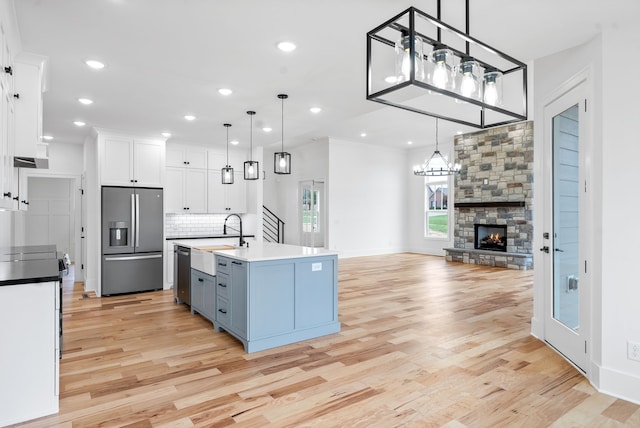 kitchen featuring stainless steel appliances, white cabinetry, pendant lighting, sink, and light hardwood / wood-style floors