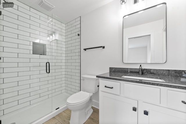 bathroom with a shower with door, vanity, toilet, and tile patterned flooring