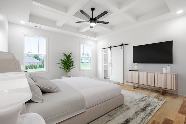 bedroom with light wood-type flooring, coffered ceiling, a barn door, and ceiling fan