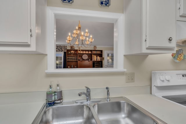 kitchen with sink, ornamental molding, white range oven, a notable chandelier, and white cabinets