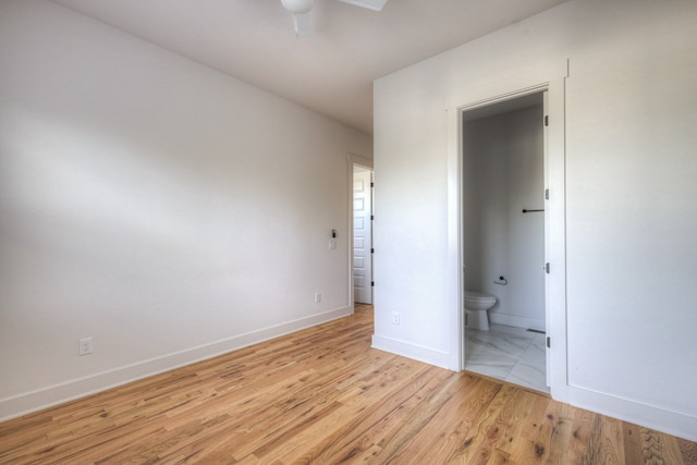 unfurnished bedroom featuring light hardwood / wood-style floors, ceiling fan, and ensuite bath