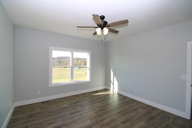 empty room featuring dark wood-type flooring and ceiling fan