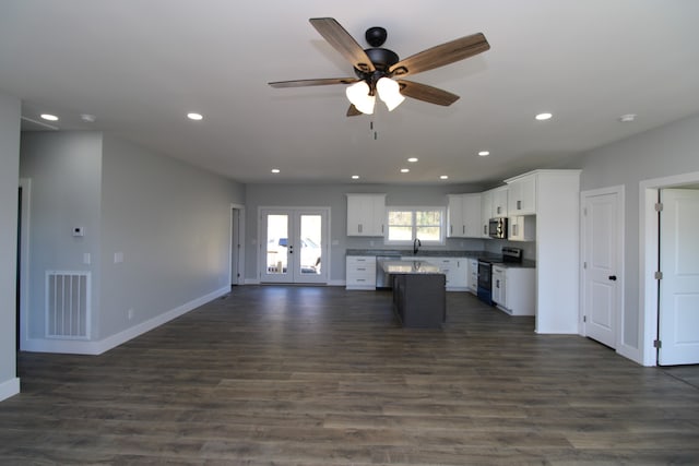 kitchen with stainless steel appliances, white cabinetry, ceiling fan, a kitchen island, and dark wood-type flooring