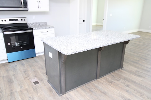 kitchen featuring white cabinetry, appliances with stainless steel finishes, light hardwood / wood-style floors, and a center island