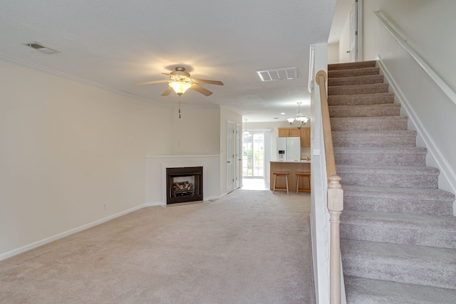 stairway featuring ceiling fan with notable chandelier and carpet floors