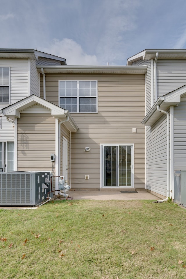 rear view of house with central AC unit, a patio area, and a lawn