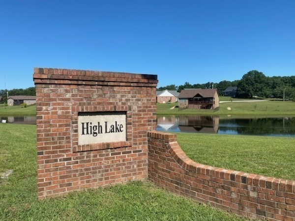 community / neighborhood sign with a water view and a yard