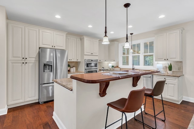 kitchen with white cabinetry, appliances with stainless steel finishes, dark hardwood / wood-style flooring, a breakfast bar, and a kitchen island with sink