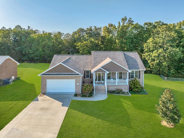 view of front of property featuring a garage, a porch, cooling unit, and a front yard