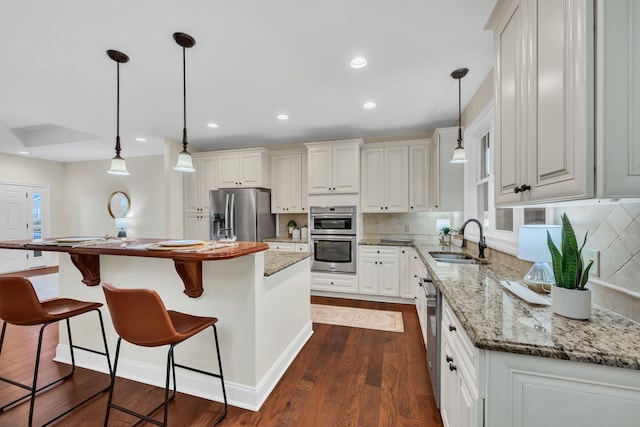 kitchen with stainless steel appliances, a kitchen island, white cabinetry, dark hardwood / wood-style flooring, and sink