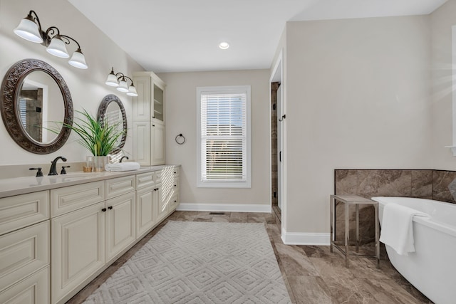 bathroom with a tub to relax in, vanity, and tile patterned floors