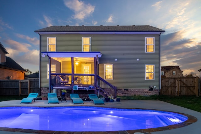 back house at dusk featuring a patio area and a fenced in pool