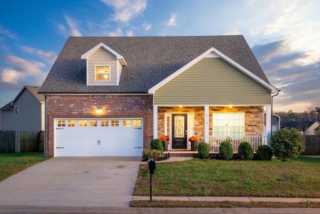 view of front of property featuring covered porch, a garage, and a lawn