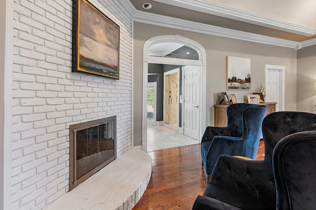 living room featuring a fireplace, hardwood / wood-style flooring, and crown molding