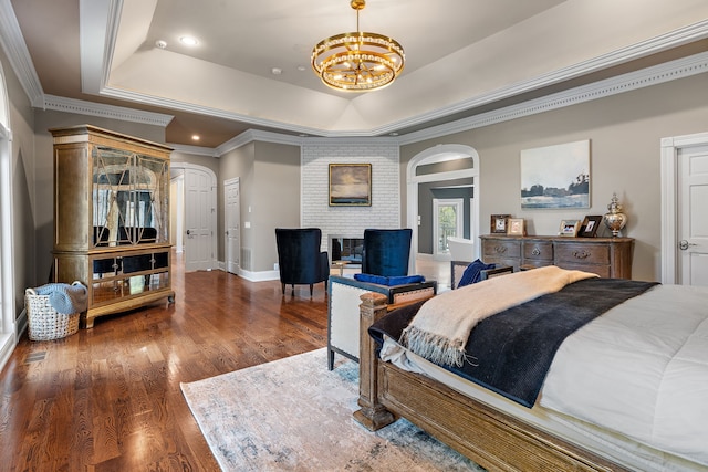 bedroom with dark hardwood / wood-style flooring, a notable chandelier, crown molding, and a tray ceiling