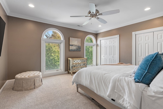 carpeted bedroom with multiple closets, ceiling fan, and crown molding