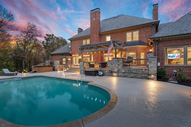 pool at dusk featuring a hot tub and a patio area