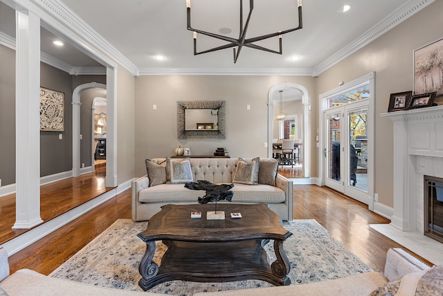 living room with a fireplace, an inviting chandelier, ornamental molding, and light hardwood / wood-style flooring