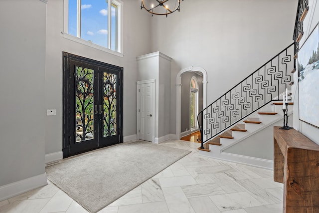 entrance foyer with a towering ceiling, an inviting chandelier, and french doors