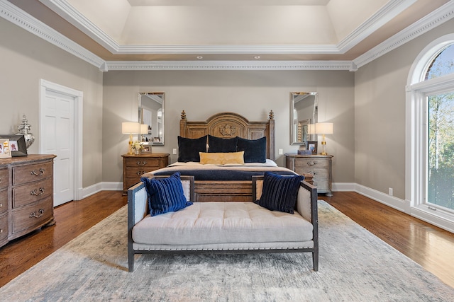 bedroom featuring dark wood-type flooring, crown molding, and a tray ceiling