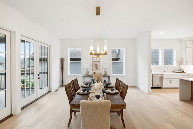 dining space featuring light hardwood / wood-style floors, sink, a wealth of natural light, and an inviting chandelier