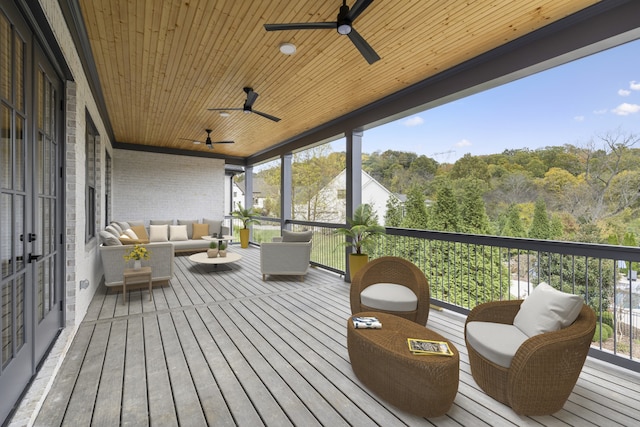 wooden deck with a wooded view, outdoor lounge area, and ceiling fan