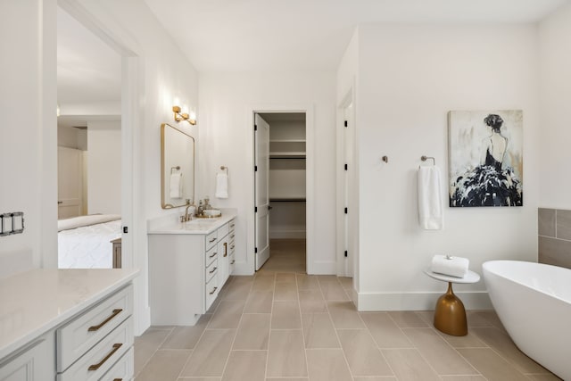 full bath featuring tile patterned floors, vanity, a walk in closet, and a freestanding tub