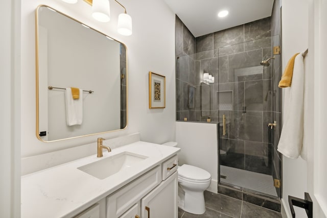 bathroom with tile patterned floors, a shower with door, vanity, and toilet