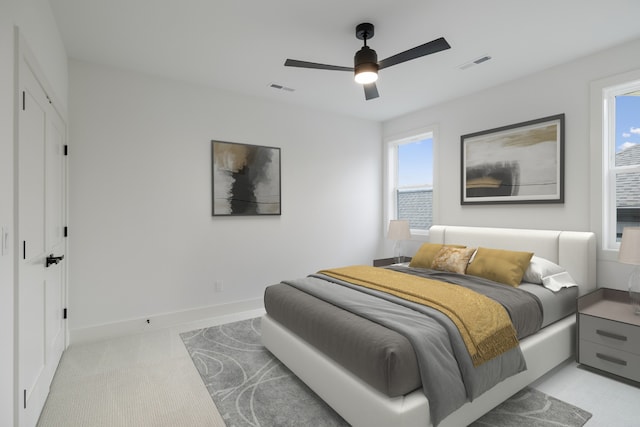 bedroom featuring light carpet, visible vents, a ceiling fan, and baseboards