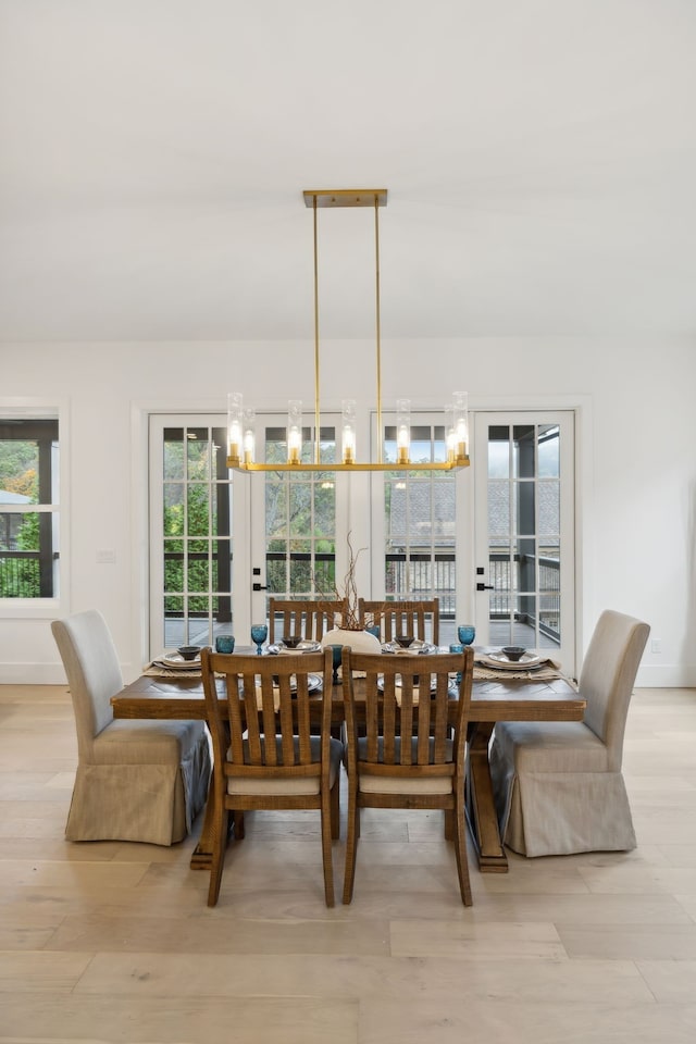 dining room featuring a healthy amount of sunlight, light hardwood / wood-style flooring, and a notable chandelier