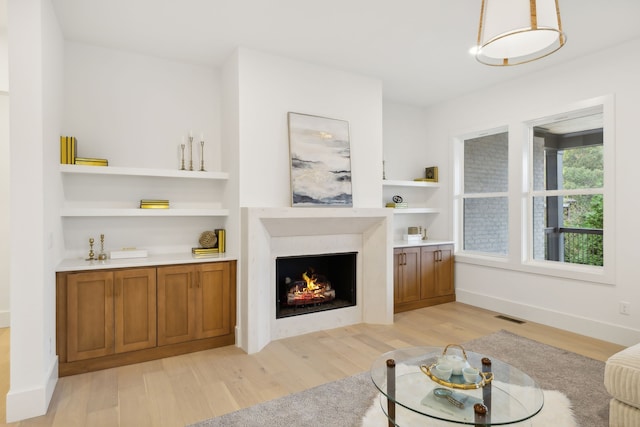 living room featuring built in shelves and light hardwood / wood-style floors