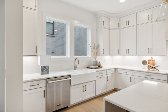 kitchen with white cabinetry, light hardwood / wood-style flooring, stainless steel dishwasher, and sink