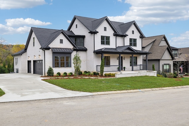 modern farmhouse style home featuring a standing seam roof, a front yard, an attached garage, and covered porch