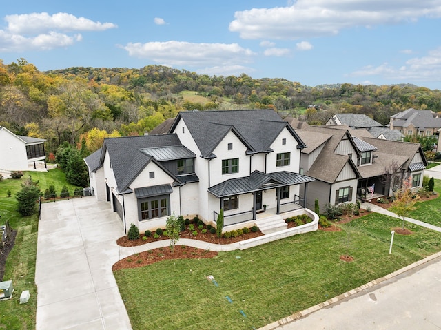 modern inspired farmhouse featuring a front yard, roof with shingles, driveway, and a standing seam roof