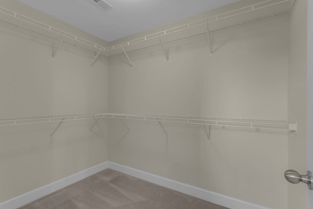 walk in closet featuring light colored carpet