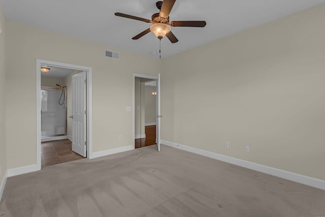 unfurnished bedroom featuring ceiling fan, ensuite bathroom, and light colored carpet