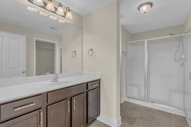 bathroom featuring a shower with shower door, vanity, and tile patterned floors