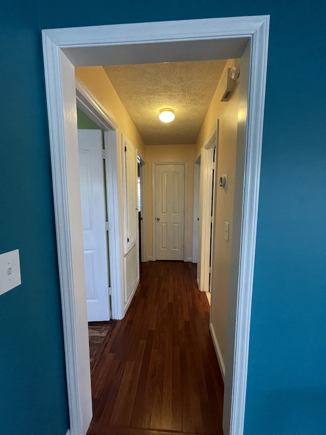 hallway featuring a textured ceiling and dark hardwood / wood-style floors