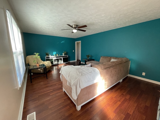 bedroom with a textured ceiling, dark wood-type flooring, and ceiling fan