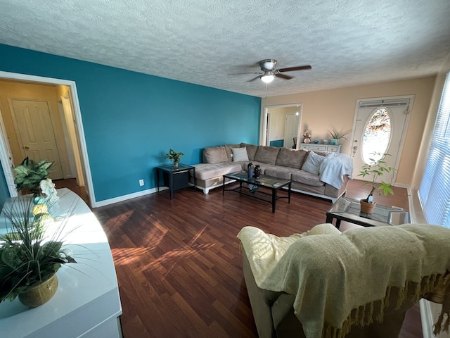 living room featuring dark wood-type flooring, ceiling fan, and a textured ceiling