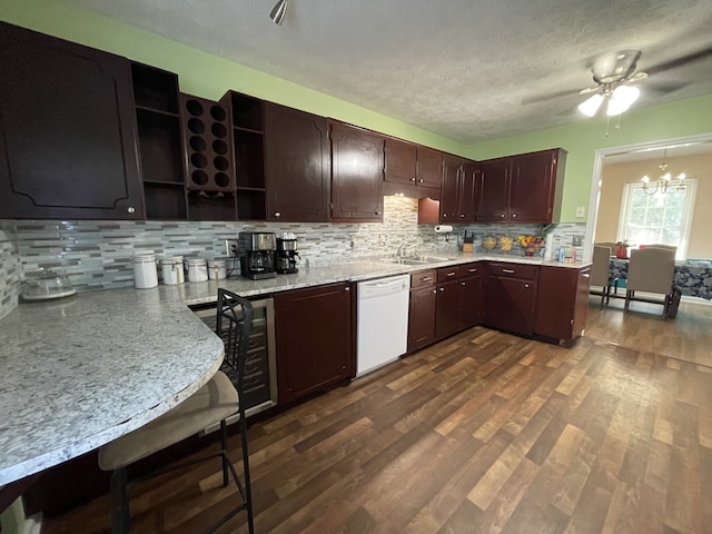 kitchen with dark wood-type flooring, white dishwasher, hanging light fixtures, a textured ceiling, and tasteful backsplash