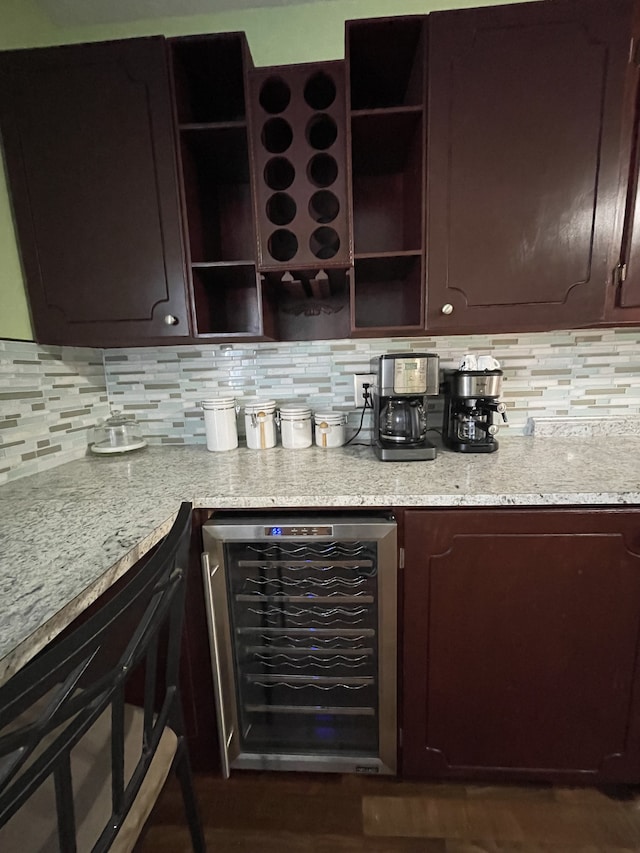 interior space featuring wine cooler, backsplash, dark brown cabinets, and light stone countertops