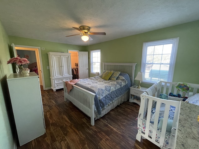 bedroom featuring dark hardwood / wood-style flooring, multiple windows, a textured ceiling, and ceiling fan