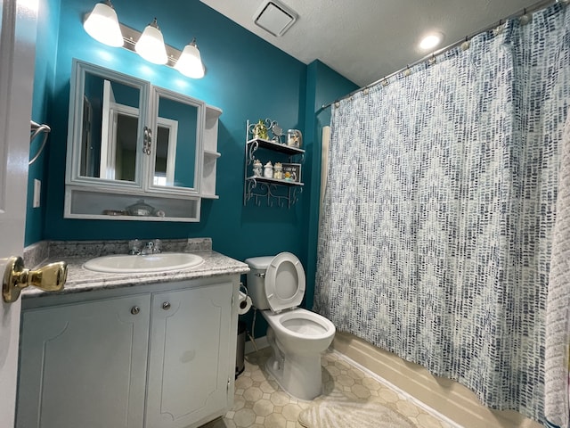 bathroom with toilet, vanity, a textured ceiling, and tile patterned flooring