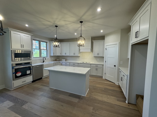 kitchen featuring white cabinetry, a center island, hanging light fixtures, stainless steel appliances, and custom exhaust hood