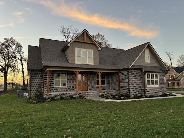 view of front facade featuring a porch, a yard, and central AC unit