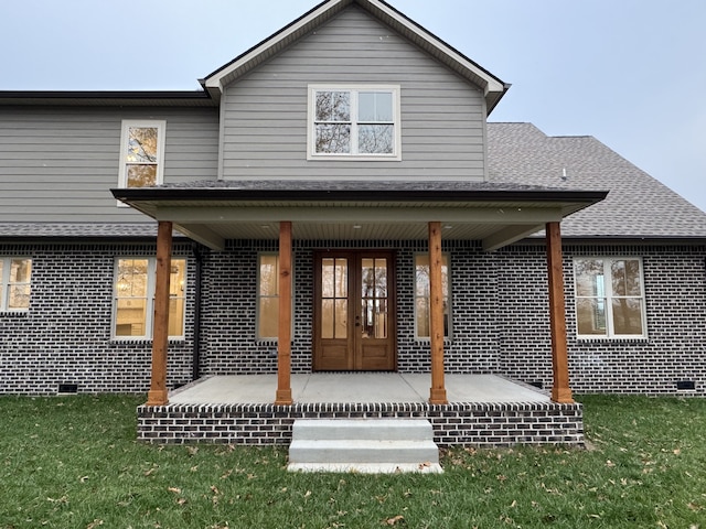 rear view of property featuring covered porch, french doors, and a lawn