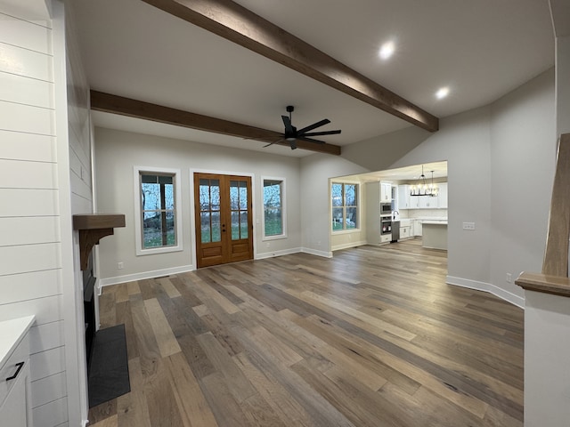 unfurnished living room featuring a large fireplace, a healthy amount of sunlight, wood-type flooring, and french doors