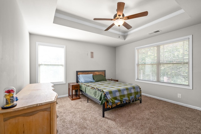 carpeted bedroom with a raised ceiling, multiple windows, and ceiling fan