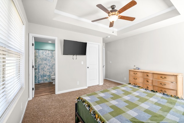 carpeted bedroom with a tray ceiling, ensuite bathroom, and ceiling fan